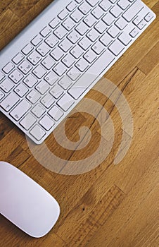 Top view of a computer monitor with a blank screen on a pure white background of a brick wall and a keyboard and mouse on a wooden