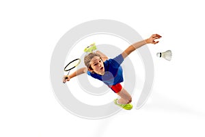 Top View. Concentrated teen boy in uniform playing badminton, hitting shuttlecock with racket isolated over white