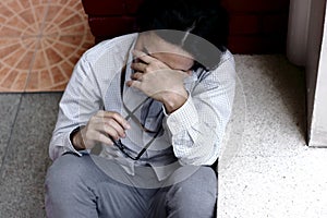 Top view of confused stressed Asian business man close his eyes and covering face with hands.