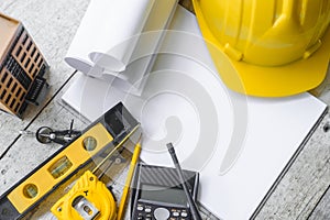 Top view construction tools such as a yellow hard hat, spirit level, measuring tape