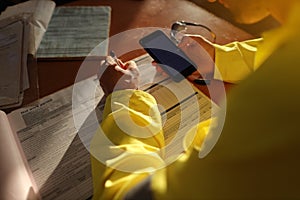 Top view of construction worker setting on the chair holding cell phone and writing emergency site phone number