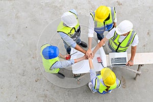 Top view of contractors, engineers and formats team in safety vests with helmets working with laptops, standing on under-