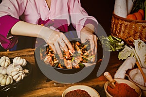 Top view Cooking Korean pickled kimchi, a Korean food dish by a woman wearing a hanbok sitting, mixing the chilies and fresh veget