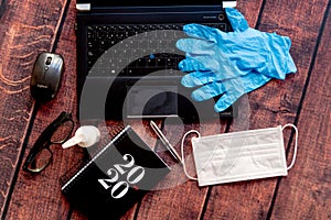 Top view of coronavirus remote work kit on wooden office desk with hand sanitizer and face mask, a solution against the spread of photo