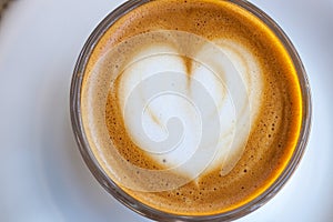 Top view of cortado coffee in a glass with the foam in shape of heart photo