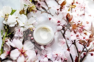 Top view of cosmetic cream with pink cherry flowers in a blue glass jar. Hygienic skincare lotion product