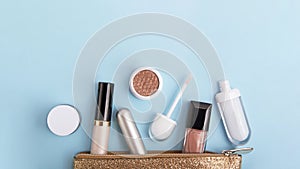 Top view of the cosmetic for make up on the blue background.Golden cosmetics bag with containers,large banner