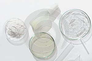top view of cosmetic product in glass bottle and petri dish with medium and test tube on a laboratory table. lab