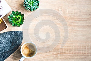 Top view of cosy home scene. Books, woolen blanket, cup of coffee and succulent plants over wooden background. Copy space