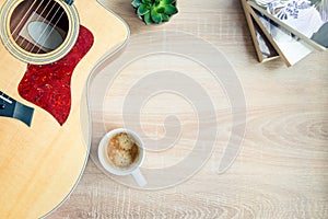 Top view of cosy home scene. Guitar, books, cup of coffee and succulent plants over wooden background. Copy space