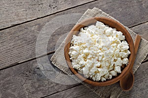 top view of cottage cheese in brown wooden bowl with spoon