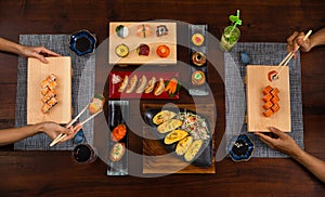 Top view of couple enjoying Japanese cuisine various side dishes by chopstick. Philadelphia, Tuna uramaki, Flower sush set,