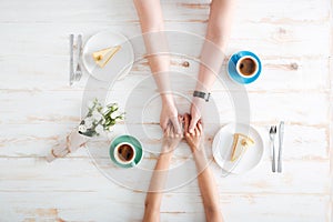 Top view of couple holding hands and eating dessert