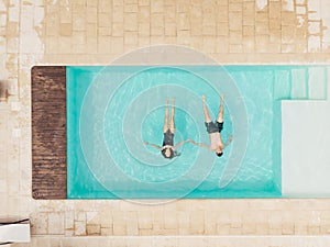 top view of couple lying in swimming pool and holding hands