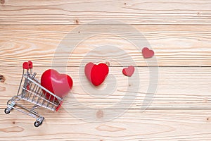 Top view couple red heart shape with mini shopping cart on wooden table. love, shopping and Valentine Day