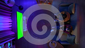 Top view of couple sitting on the sofa in the room and losing video game on TV with Chroma key green screen, advertising