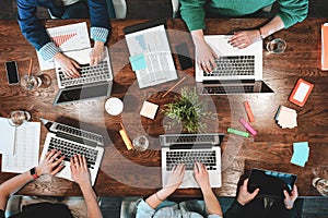 Top view of coworking people sitting together around table. Business meeting of young creative hipsters