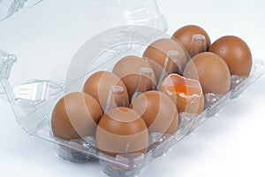 Top view of cracked fresh egg and whole eggs with bright yolk in plastic tray for eggs.