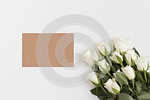 Top view of a craft card mockup with a bouquet of roses on a white table