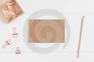 Top view of a craft card mockup with workspace accessories on a white table