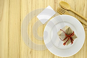 top view of craft gift box on dish on wood background concept food for gift
