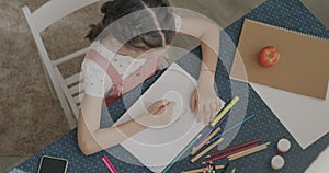 Top view of creative little girl drawing portrait concentrated on art enjoying leisure time at home