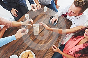 Top view creative photo of friends sitting at wooden table. Friends having fun while playing board game