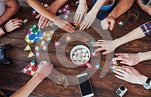 Top view creative photo of friends sitting at wooden table. having fun while playing board game