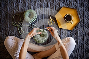 Top view creative woman knitting use ribbon yarn and crochet needle sitting on warm white plaid