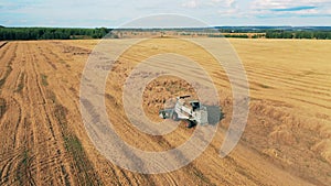 Top view of a crops field getting reaped by a combine