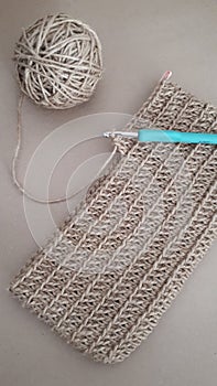Top view of a crotchet fabric with a needle and a roll of yarn