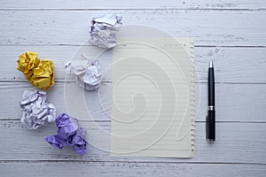 Top view of crumple paper ball and notepad on table