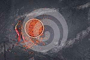 Top view of crushed dry red hot chili pepper in wooden bowl