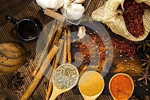 Top view of culinary seasonings & herbs, hot red chilli, white pepper, dried chilli powder in spoons, garlic, spices  in sacks,