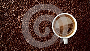 Top view of cup of black coffe put it on coffe beans background