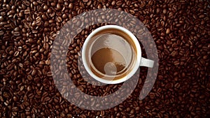 Top view of cup of black coffe put it on coffe beans background