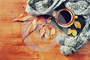 Top view of Cup of black coffee with autumn leaves, a warm scarf and old book on wooden background. filreted image/