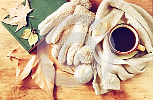 Top view of Cup of black coffee with autumn leaves, a warm scarf and old book on wooden background. filreted image.