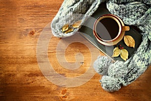 Top view of Cup of black coffee with autumn leaves, a warm scarf and old book on wooden background. filreted image.