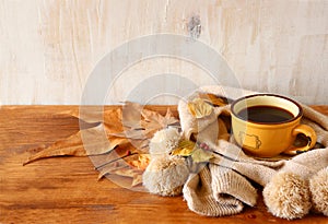 Top view of Cup of black coffee with autumn leaves, a warm scarf on wooden background. filreted image