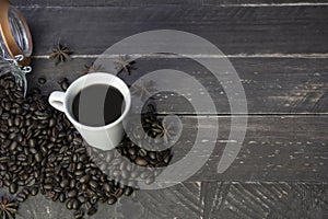 Top view of a cup of black coffee with coffee beans on wooden table.Coffee vintage wood background with big copy space for text