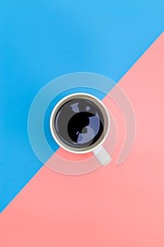 Top view of cup of black coffee on pink and blue background, A cup of black coffee on blue background. View from above