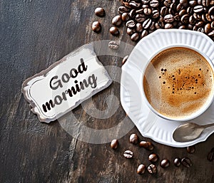 Top view of a cup of black strong coffee on a wooden table with coffee beans scattered around and a sign with the text \