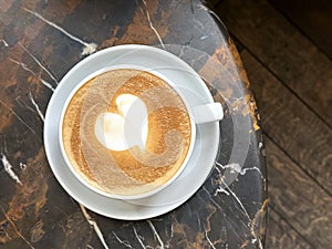 Top view of cup of cappuccino coffee with latte art on marble table