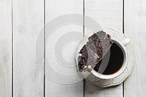 Top view of a cup of coffee with a Chocolate Biscotti on a wooden table with copy space