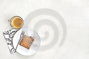 Top view of a cup of coffee and a dessert plate with brownie cake over white rustic background