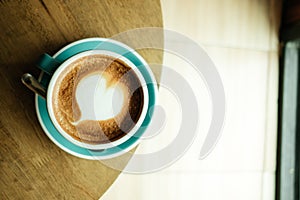 Top view. cup with coffee has a heart shape on top both placed o