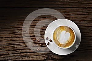 Top view of a cup of the coffee latte heart shape and coffee beans on old wooden background