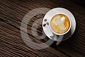 Top view of a cup of coffee latte tree shape and coffee beans on old wooden background