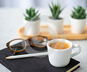 Top view cup of coffee with notebook, pencil and the glasseson wooden table background, modern lifstye concept